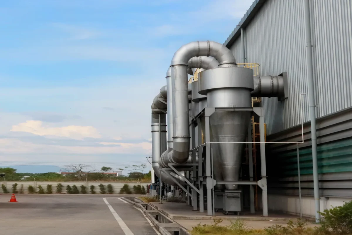 Industrial dust collection equipment and ductwork beside a factory