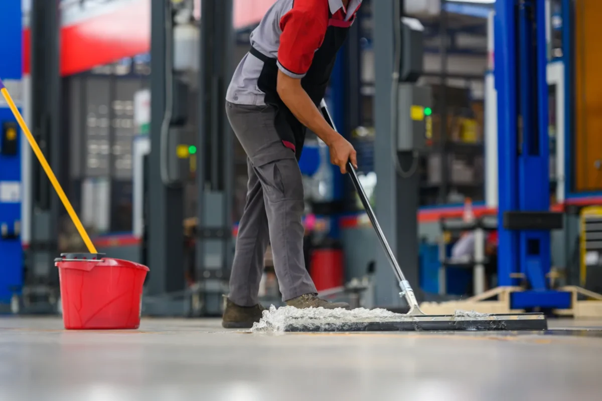 Worker mopping the floor of a vehicle workshop