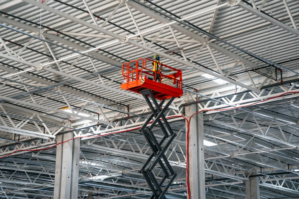 Scissor lift providing access to overhead steelwork inside an industrial building
